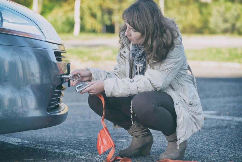 Blog image - woman assembling towing hook to a broken car
